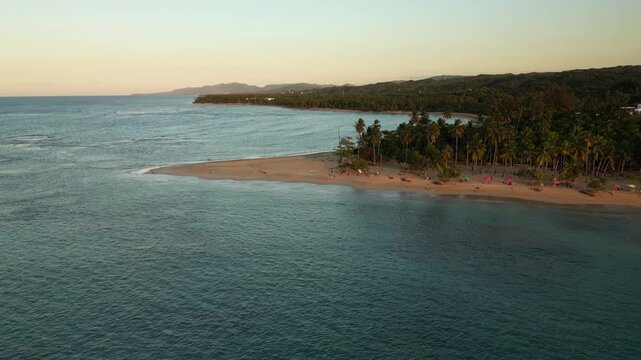 A cinematic golden hour over Punta Popy Beach, Dominican Republic. Drone captures tranquil ocean waves, tropical palms, and catamarans resting offshore&mdash;ideal for tourism, wellness, and lifestyle video