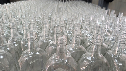 A close-up shot of a set of six empty glass bottles arranged on an assembly line in a factory