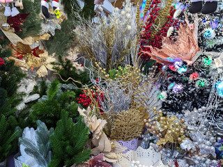 A rich display of Christmas decorations with gold and silver glitter foliage, red berries, and festive ornaments