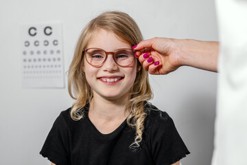 smiling child with try on optical glasses after eye test at optometrist visit. eyesight correction