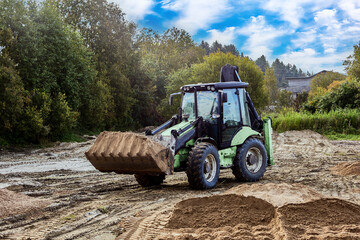 Wheel mounted earthmover spreads material on work area, preparing base for upcoming construction tasks.