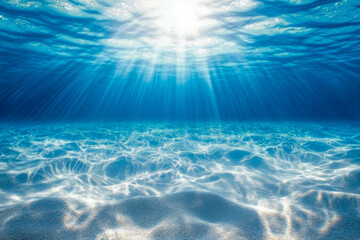 Sunlight shines through clear ocean water, illuminating the tranquil underwater scene and highlighting the gentle waves and sandy bottom
