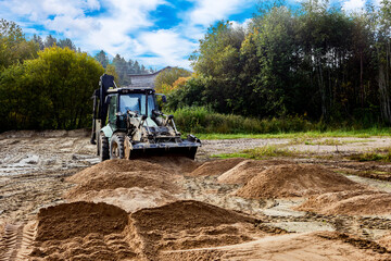 Digger spreads material uniformly, preparing site for upcoming development.