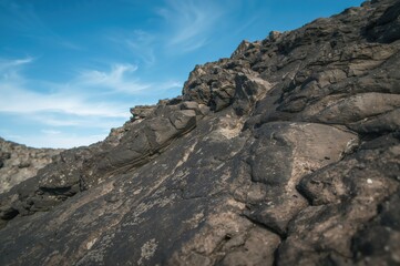 Detailed view of rough basalt stones beneath a bright sky, highlighting natural textures and geological designs.
