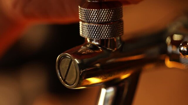 Bartender pulls a modern chrome tap handle to pour fresh craft beer. Taps are mounted on wooden barrels in a dark pub setting. Perfect for showcasing bar atmosphere and beverage service.