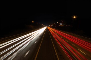 Long exposure photo showing bright car light trails illustrating fast vehicle movement on a nighttime road