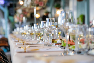 glasses on the table. wedding table setting.  close-up of elegant wine glasses on a long banquet table set for a luxury wedding or fine dining event with shallow depth of field