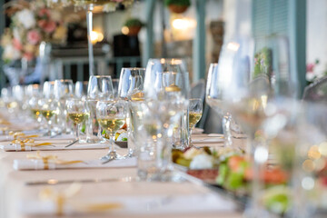 wedding table setting.  close-up of elegant wine glasses on a long banquet table set for a luxury wedding or fine dining event with shallow depth of field