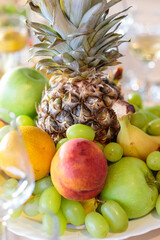 Vibrant, fresh fruit platter centerpiece with pineapple, green and red apples, juicy grapes, peach, and orange, set on a bright table for a celebration or healthy dessert