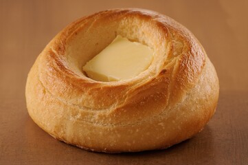 Delicious crusty bread roll with butter, prepared for eating.