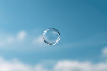 Soap bubble floats up against a bright blue backdrop