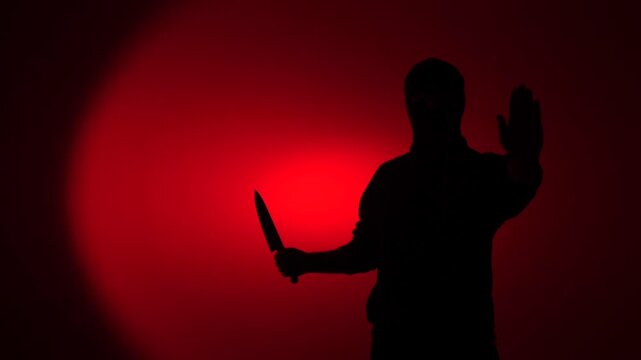 Silhouette man holding knife stopping threat, hand in a stopping gesture, danger, crime, horror