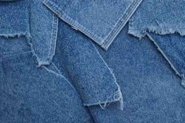 Fototapeta premium Samples of distressed denim fabric in blue hues. Torn and ripped denim textile pieces, banner backdrop. Repurpose worn denim material. Various denim cloth fragments.