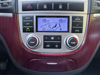 Modern car climate control system displays temperature settings and fan controls in a stylish interior setting with a wooden finish and sleek design elements