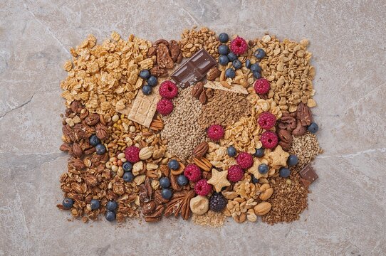 Nutritious treat featuring cereal, granola, nuts, and fresh berries arranged on a stone surface, top-down view - Powered by Adobe