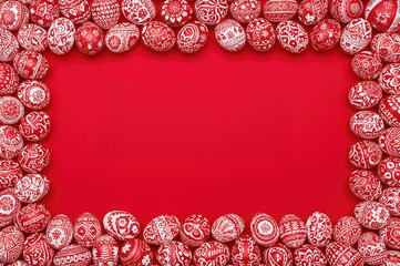 Rectangular frame of red and white eggs on a vivid red backdrop for Easter, flat lay with space for text.