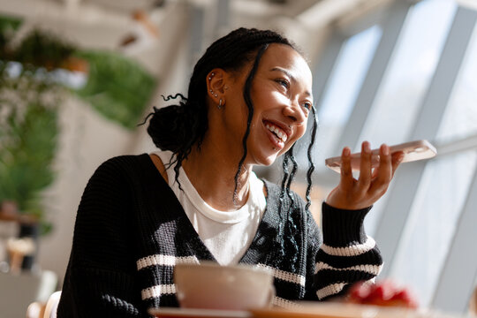 Woman laughing recording voice message on smartphone