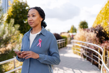 Black woman wearing pink ribbon for cancer awareness