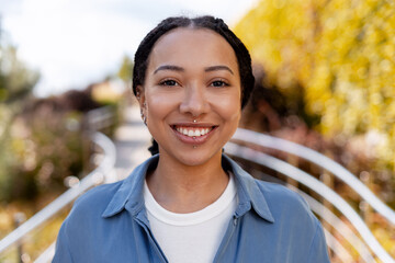 Young woman smiling outdoors having lip and nose piercings