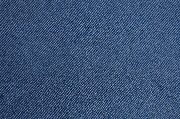 Extreme close-up of distressed blue denim fabric texture with diagonal weave pattern.
