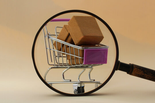 Magnifying glass searches and finds shopping cart with cardboard boxes