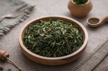 Fototapeta premium Wooden bowl filled with dry green organic oolong leaves