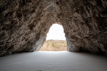 Rock cave opening isolated on a white background. Perspective from within the cave.