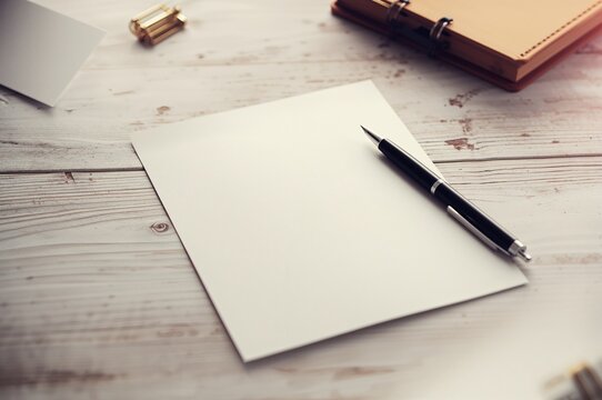 Empty notebook with a pen resting on a wooden surface, isolated workspace setup