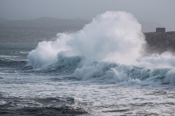 Emotion at sea: Powerful wave smashing against rocky shore with spray and foam