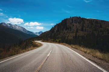 Naklejka premium Deserted highway and mountain landscape beneath a clear blue sky
