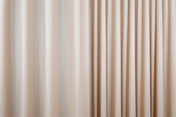 Textured beige fabric used for curtains as a backdrop. Expansive drape material. Fabric suitable for hospitality displays. Light cream textile. Portrait orientation.