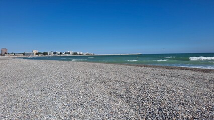 Peaceful sandy beach covered with seashells. Beautiful waves of the Black Sea.