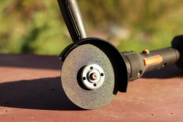 Angle grinder with battery. Power tool close-up. Angle grinder on the veranda. Repair and construction tool. Angle grinder with handle