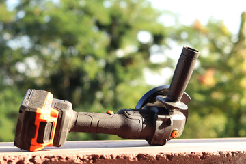 Angle grinder with battery. Power tool close-up. Angle grinder on the veranda. Repair and construction tool. Angle grinder with handle