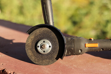 Angle grinder with battery. Power tool close-up. Angle grinder on the veranda. Repair and construction tool. Angle grinder with handle