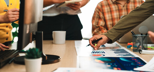 A diverse business team collaborates in a modern office setting, analyzing charts and graphs for marketing strategy. Focused discussions drive productivity and innovation. SACTR