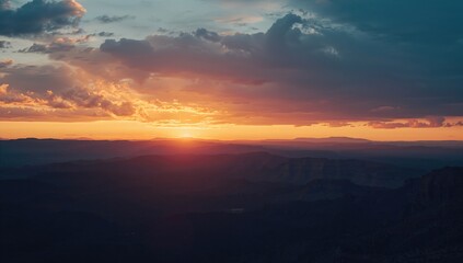Fototapeta premium Wide-angle view of mountain range under a vibrant twilight sky with clouds at sunset