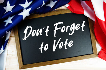 American flag with blackboard  "Don't Forget to Vote" on wooden background
