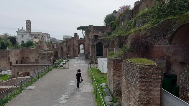 Fashion skylish female model walk visiting ancient Roman Forum in Rome, Italy, aerial drone view