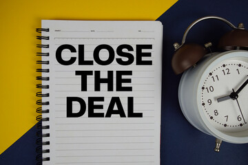 Close the Deal text written on notepad with alarm clock on yellow background