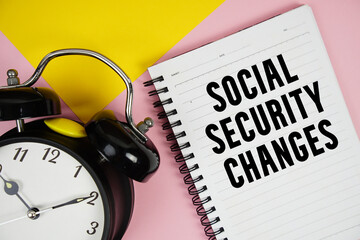Social Security Changes text written on notepad with alarm clock on pink background