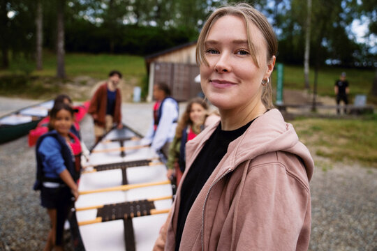 Portrait of smiling young female camp counselor in forest with kids