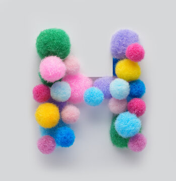 Colorful letter H made of fluffy pom poms on white background. Creative handmade typography for kids learning alphabet, educational design, playful classroom decor, and graphic projects.