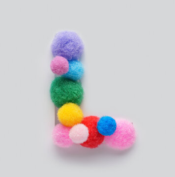 Colorful letter L made of fluffy pom poms on white background. Creative handmade typography for kids learning alphabet, educational design, playful classroom decor, and graphic projects.