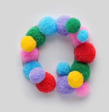 Colorful letter Q made of fluffy pom poms on white background. Creative handmade typography for kids learning alphabet, educational design, playful classroom decor, and graphic projects.