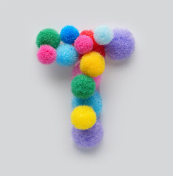 Colorful letter T made of fluffy pom poms on white background. Creative handmade typography for kids learning alphabet, educational design, playful classroom decor, and graphic projects.