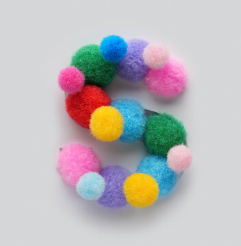 Colorful letter S made of fluffy pom poms on white background. Creative handmade typography for kids learning alphabet, educational design, playful classroom decor, and graphic projects.