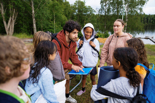 Male instructor explaining guidelines to kids at summer camp