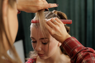 Stylist sectioning strands with comb during salon hairstyle prep closeup