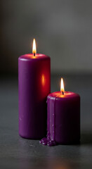 Elegant purple pillar candles glow with warm, inviting light, casting soft reflections on a dark surface, perfect for serene ambiance and relaxation.